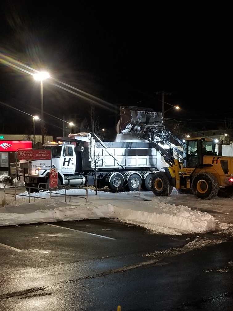 Hunter Environmental front end loader dumping snow into dump truck