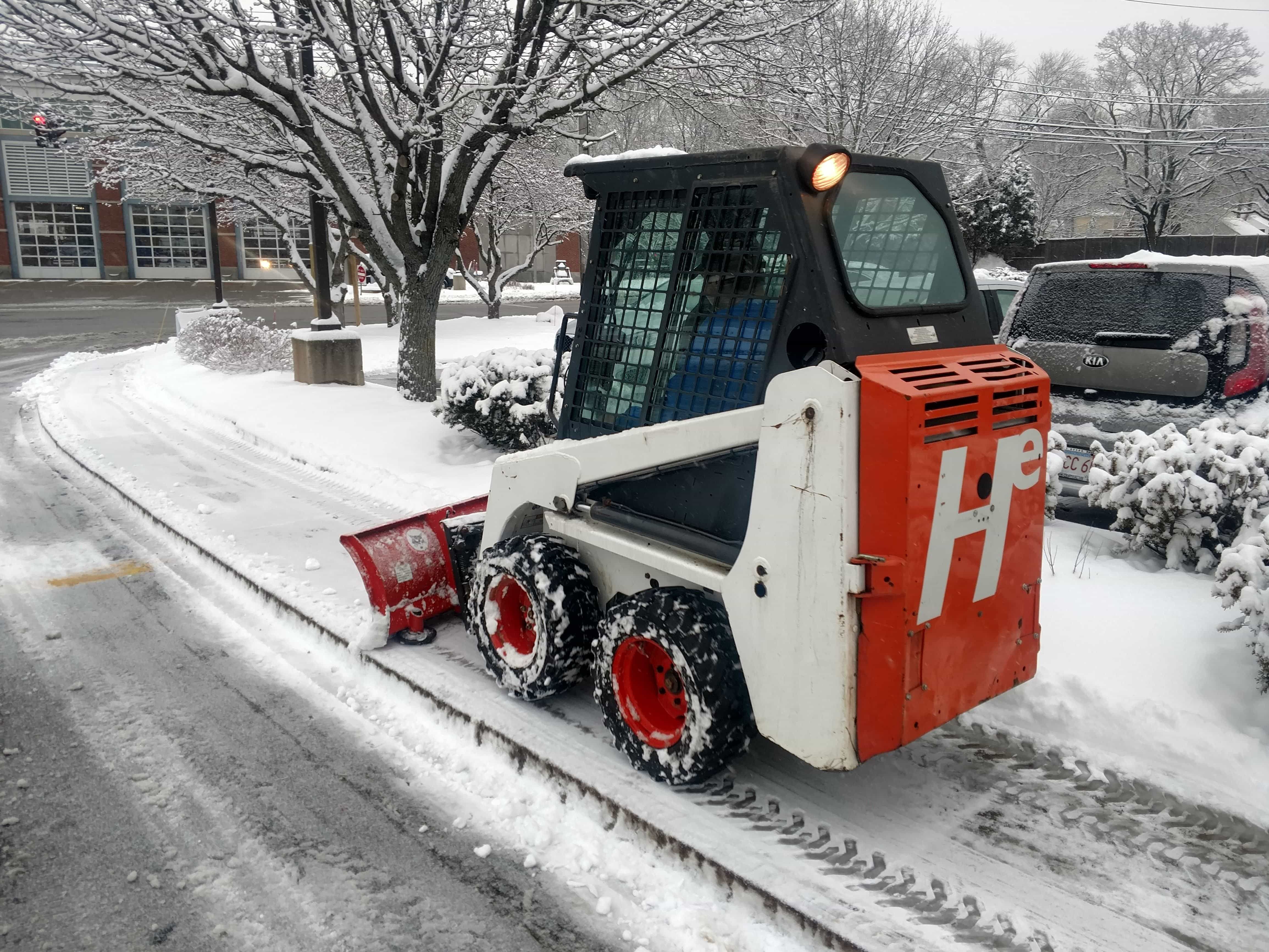 Skid steer plowing sidewalk