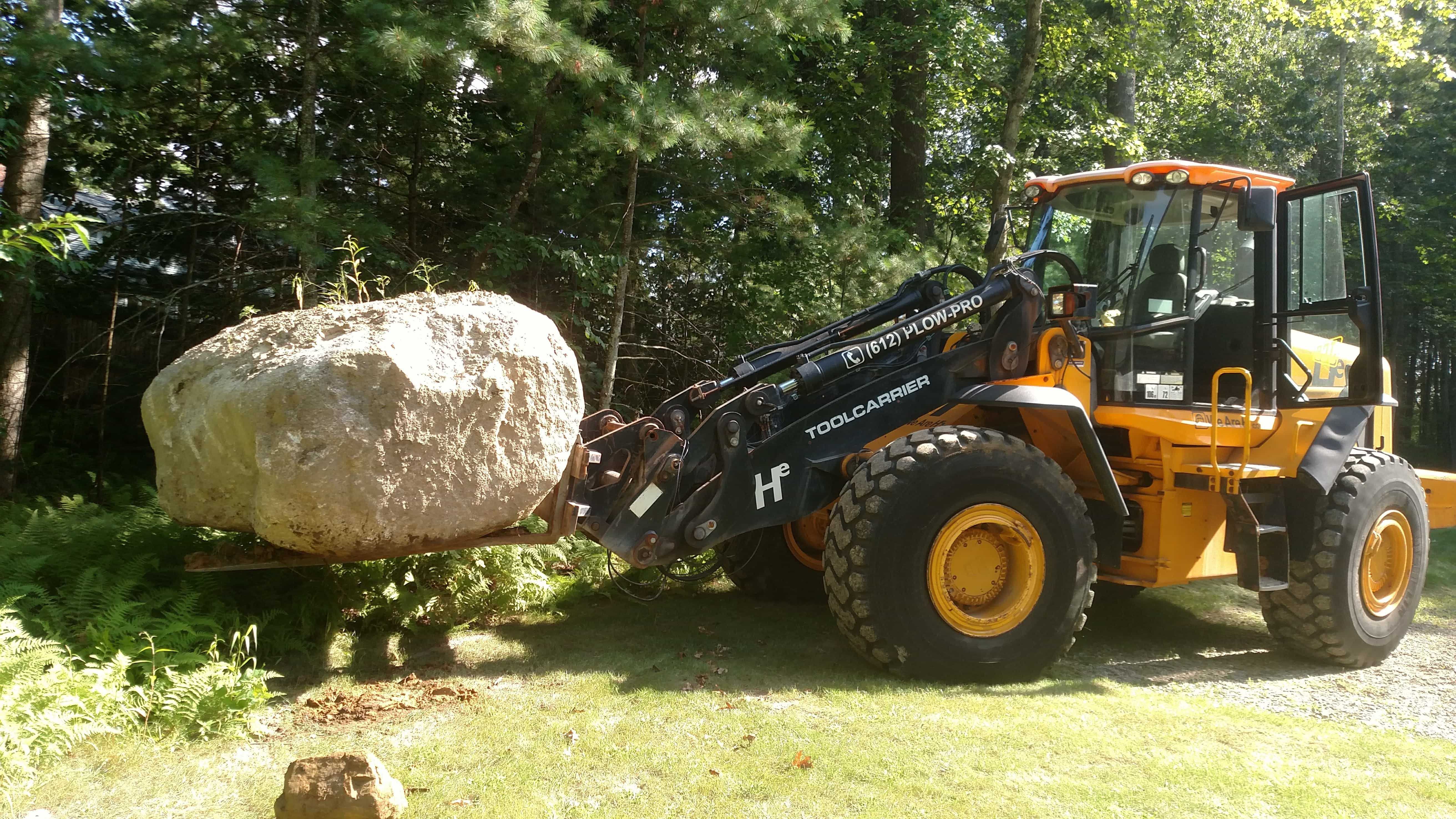 Front end loader moving a boulder